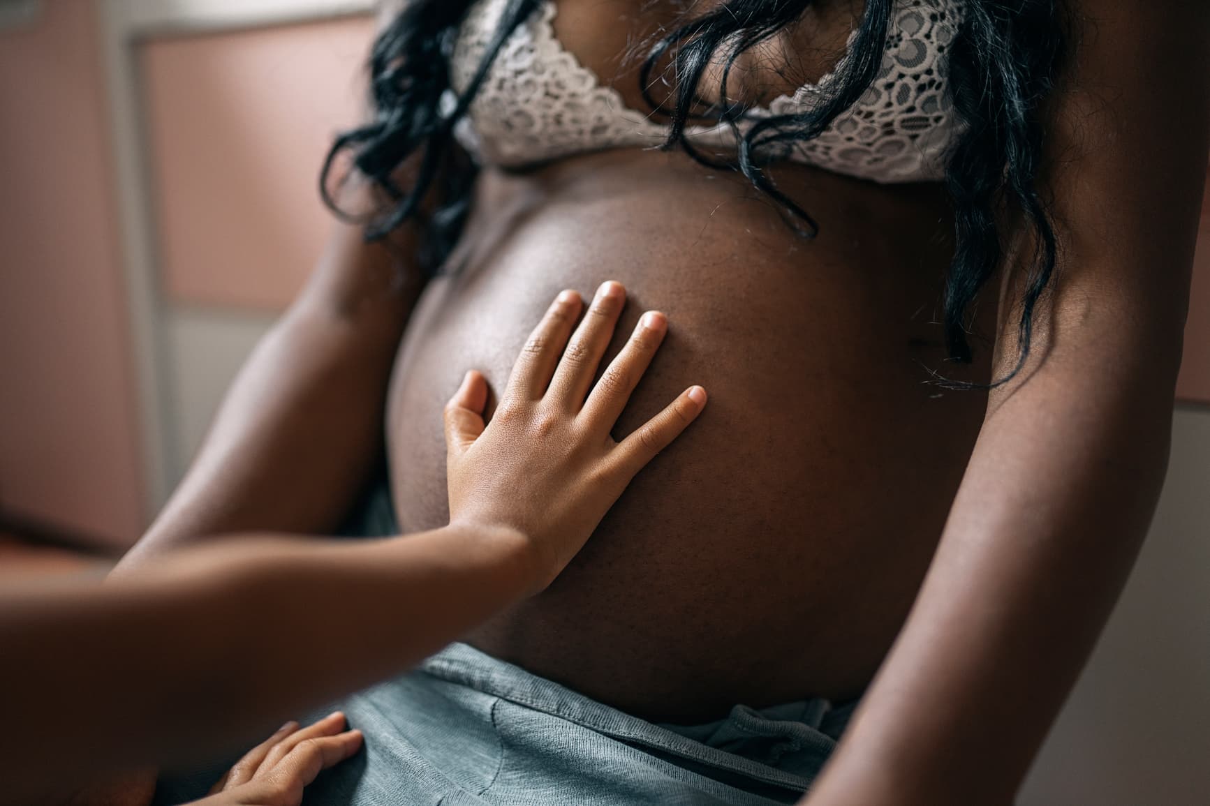 Child’s hand resting on a pregnant belly, capturing family bonding, pregnancy connection, and anticipation of a new baby.